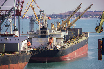 Tugboat assisting container cargo ship to harbor quayside