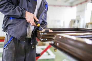 Factory for aluminum and PVC windows and doors production. Manual worker assembling PVC doors and windows. 