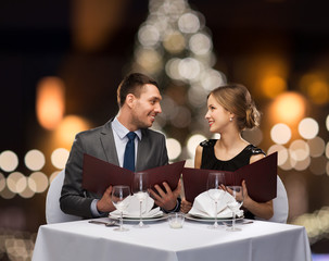 smiling couple with menus at christmas restaurant