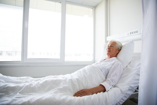 Smiling Senior Woman Lying On Bed At Hospital Ward