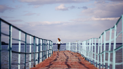 girl walking on the bridge on the lake