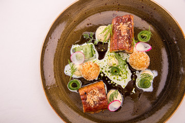 The eel glazed in kvass with croquet from cottage cheese and potatoes is served with a pickles and sauce