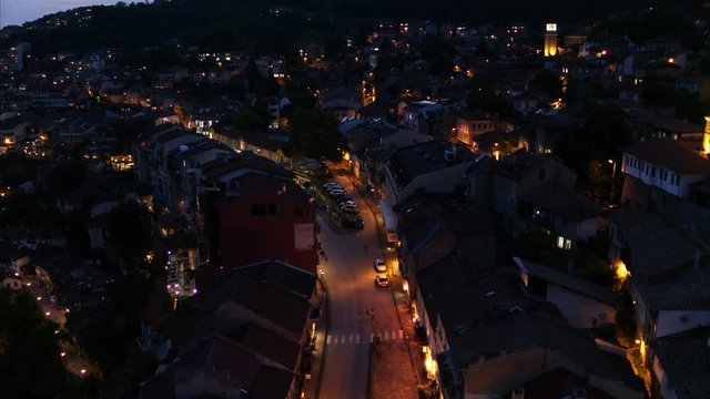 Wide flyover shot of street on urban hillside at night / Veliko Tarnovo, Bulgaria