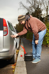 Man with plastic canister opening car tank on street for filling