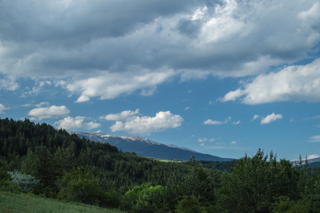 Fototapeta na wymiar Snowy peak and green hills