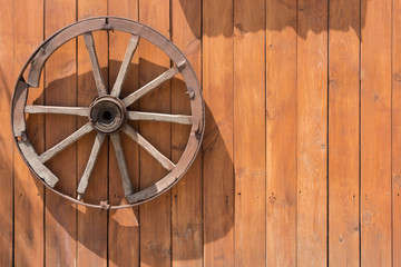 old wheel from a cart on a wooden wall