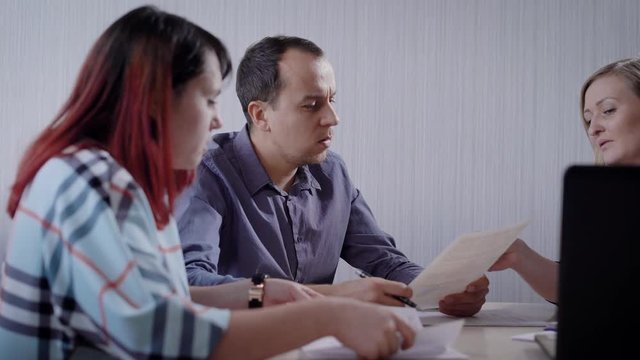 man and woman are clients of a realtor company are sitting in a customer service department and reading papers