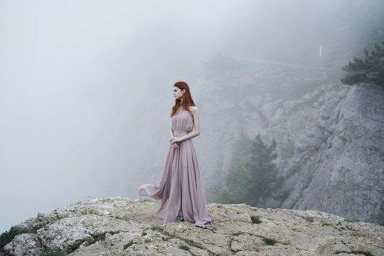 Woman wearing dress on rock in fog