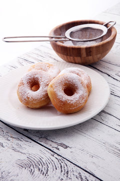powdered sugar donuts on rustic white table.