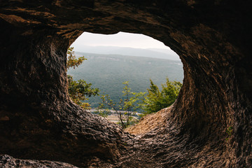 Lookout from tunnel or corridor or hole of cave at mountain peak