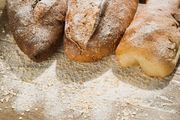 Variations of bread on the top of wooden table with flour
