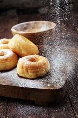 powdered sugar donuts on rustic brown table.