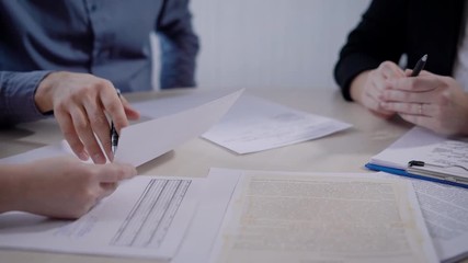 people in an office are discussing a conditions of contract, holding papers in hands, looking and reading