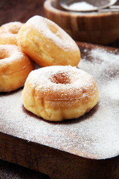 powdered sugar donuts on rustic brown table.