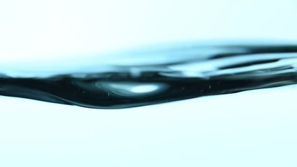 Shaking pure clear cold water surface level spinning and whirling in transparent glass jar or teapot, close up, low angle side view, slow motion