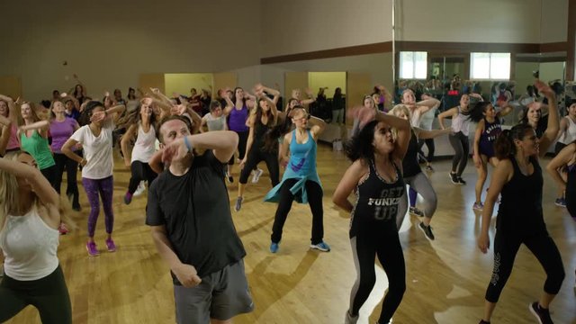 Medium panning shot of instructor running into middle of fitness class / Orem, Utah, United States