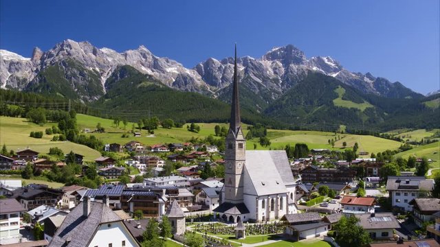 Wide aerial shot of houses and tower near mountain range / Maria Alm,, Austria