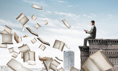 Man using smartphone and many books flying in air