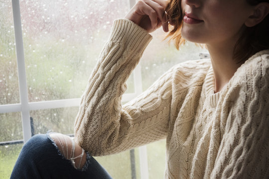 Portrait of pensive Caucasian woman near rainy window