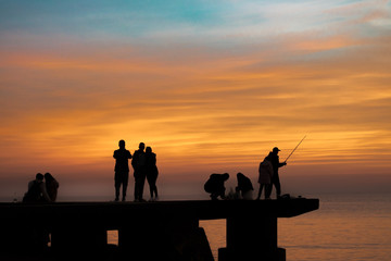 Fototapeta na wymiar People Fishing at Breakwater