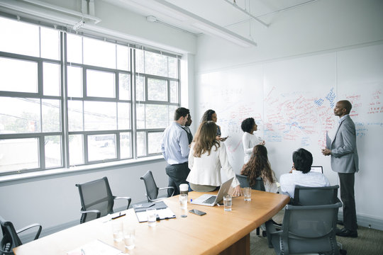 Business people talking near whiteboard in meeting