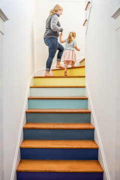 Caucasian mother and daughter climbing multicolor staircase