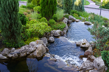 artificial pond with waterfalls in the landscape park
