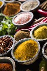 A selection of various colorful spices on a wooden table in bowls
