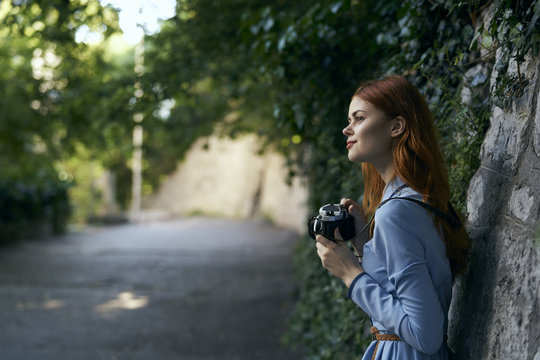 Caucasian woman photographing with camera near stone wall
