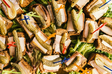 Buffet table with sandwiches of rye bread, lard and pickled cucumbers, top view closeup