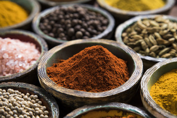 A selection of various colorful spices on a wooden table in bowls