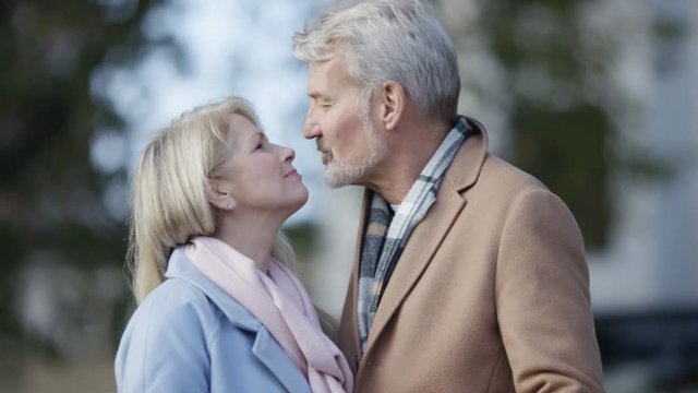Happy mature couple share a kiss whilst walking in the city