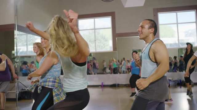 Medium panning shot of fitness instructor leading exercise class / Orem, Utah, United States