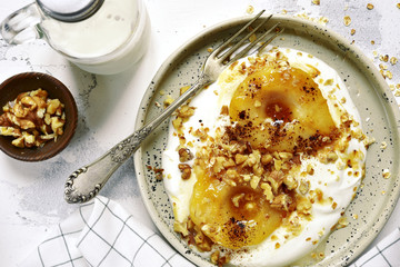 Caramelized pear with nuts and yogurt for a breakfast.Top view.