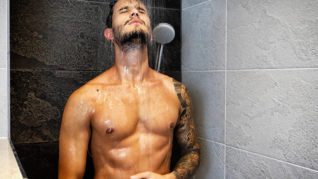 Close up of Attractive Young Bare Muscular Young Man with Tattoos Taking Shower