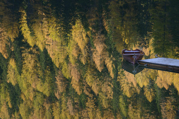 lonely boat in autumn lake with tree reflections in Italian dolomites