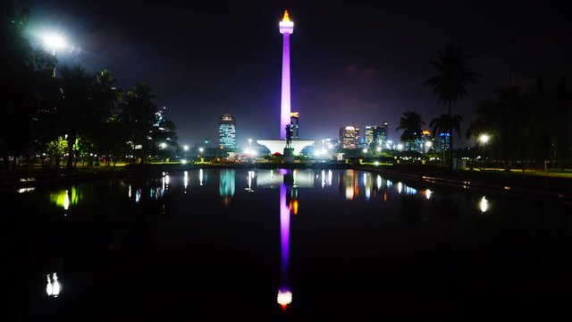 Timelapse of Monas or National Monument at night with reflection on the pool. A historical landmark placed in Jakarta, Indonesia.