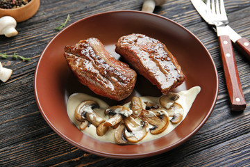 Plate with steak Diane on wooden table