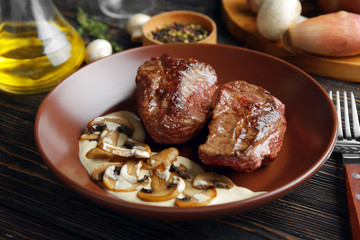 Plate with steak Diane on wooden table