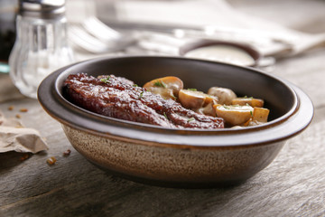 Bowl with steak Diane on wooden table