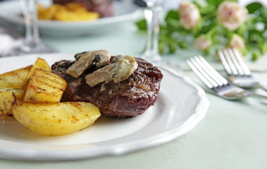 Plate with steak Diane and vegetable garnish on table