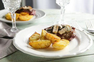 Plate with steak Diane and vegetable garnish on wooden table