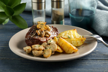 Plate with steak Diane and vegetable garnish on wooden table