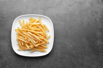 Plate with yummy french fries on table