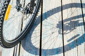 Shadow from a bicycle wheel on a wooden background