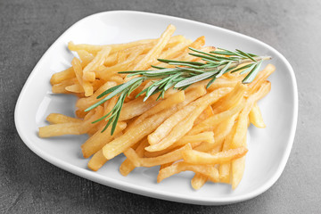 Plate with yummy french fries on table