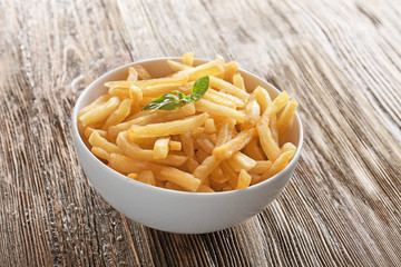 Bowl with yummy french fries on wooden table
