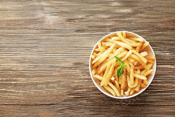Bowl with yummy french fries on wooden table