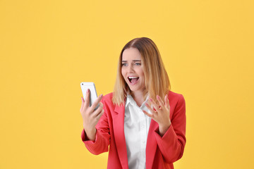 Naklejka premium Young woman using cell phone on yellow background