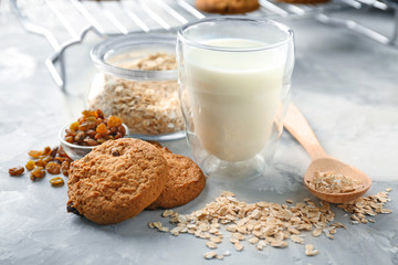 Delicious oatmeal cookies with raisins and glass of milk on table